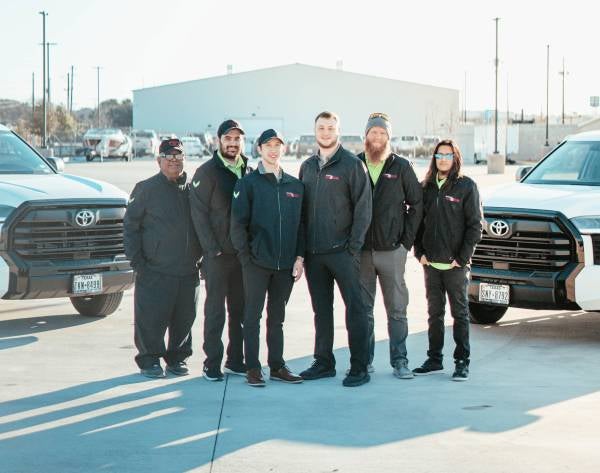 Photo of staff members posing between two trucks