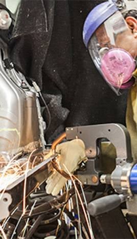 Worker grinding metal on damaged car