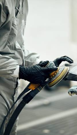 Technician sanding car body panel