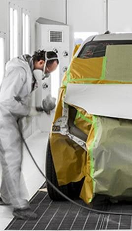 Painter sprays masked car in booth